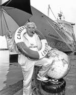 ID 4775 CANBERRA (1961/44807grt/IMO 5059953) - Veteran English TV and radio personality Sir Jimmy Savile, OBE, KCSG - 31 October 1926 - 29 October 2011) poses for the press photographers beneath the bow of...